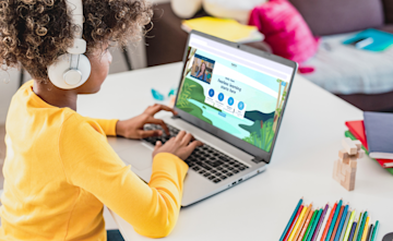 A young child sits at a desk in front of a laptop where they are using Explore Learning smart digital learning tool.